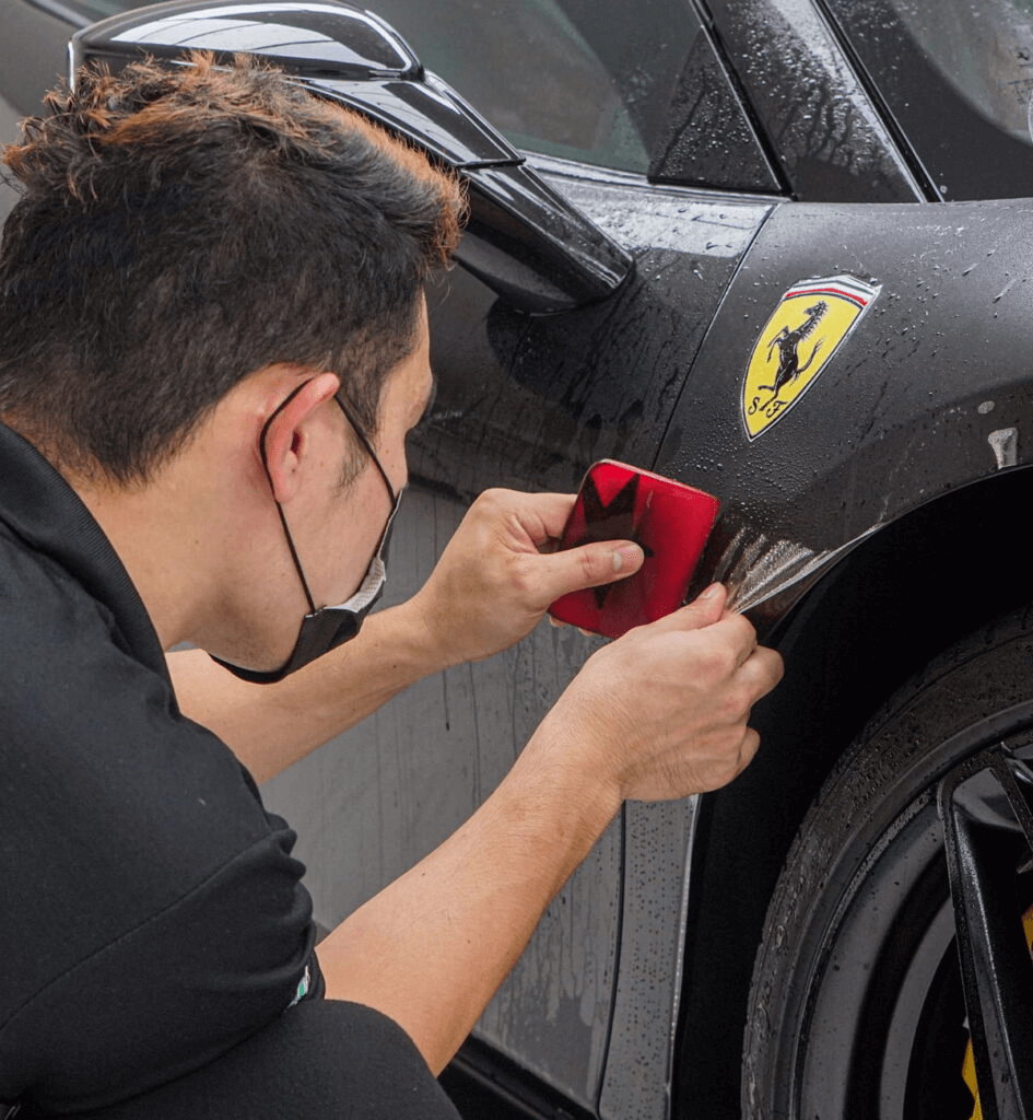 A person applying paint protection film on the car with a card